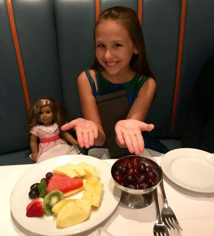 girl with doll and plate of fruit