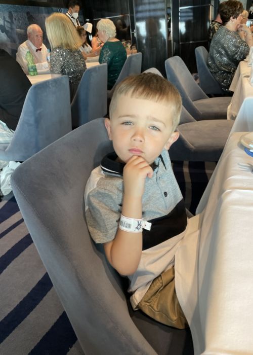 My son with a contemplative expression, sitting in a high-back dining chair on MSC Virtuosa.