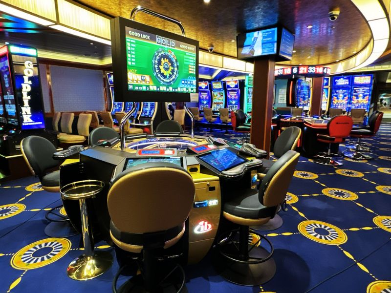 The vibrant casino on Costa Smeralda with electronic roulette tables and a variety of slot machines, all set against a decorative blue carpet with golden patterns, creating an exciting gaming atmosphere.