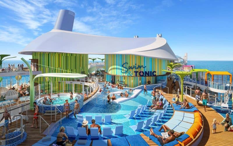 Busy pool deck scene at 'Chill Island' on Royal Caribbean's 'Icon of the Seas,' featuring a large, vibrant swimming area. Guests relax in blue sun loungers and enjoy the water in circular pools, while others gather under a large white canopy. The area is accented with colorful, vertical stripes, creating a lively, vacation-ready atmosphere.