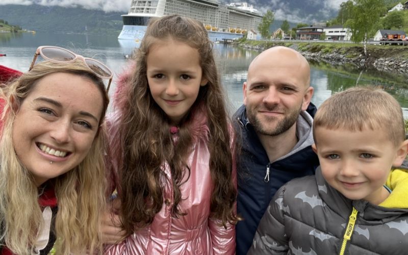 Cruise mummy and her family flashing a beautiful smile behind a cruise ship