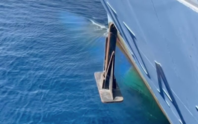 A cruise ship's anchor deployed at sea, with a view of the ship's hull and the ocean waves.