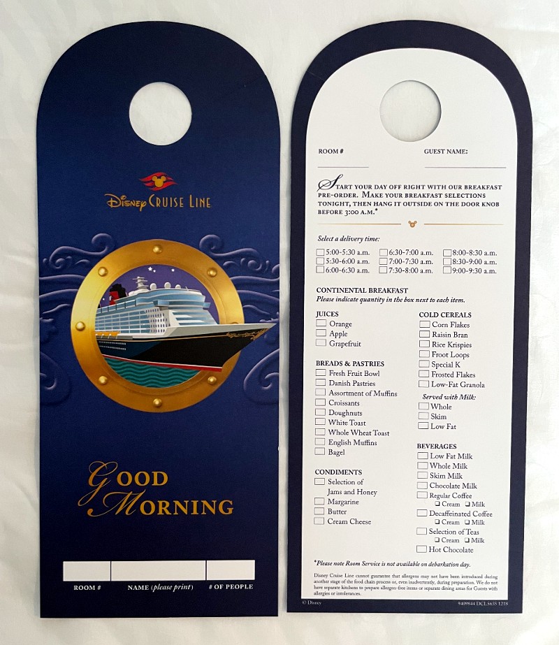 A room service breakfast menu from the Disney Wish cruise ship. It is designed as a door hanger with sections for room number, guest name, and number of people. The left side features vibrant graphics with a "Good Morning" greeting and an illustration of the ship viewed through a porthole. The right side lists breakfast options under several categories including juices, cold cereals, breads & pastries, condiments, and beverages. Options range from various juices, an assortment of cereals, and different bread types to a selection of teas and coffees. This menu allows guests to pre-order their breakfast and choose a specific delivery time, enhancing the convenience and personalized experience onboard.