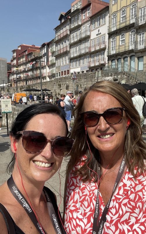 Cruise mummy and Cruise Granny taking a selfie with the buildings behind them while wearing cruise ship exclusive earphones