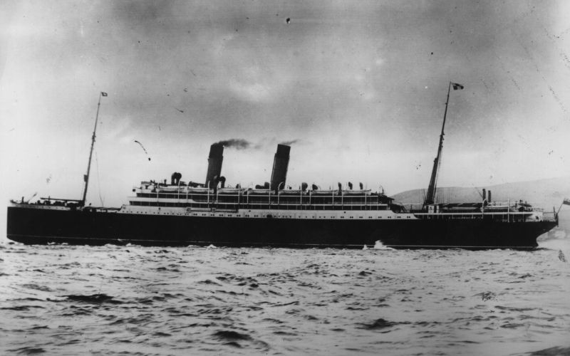 Vintage black and white photograph of the RMS Empress of Ireland, an early 20th-century ocean liner, depicted with two funnels billowing smoke as it cruises on the open sea.