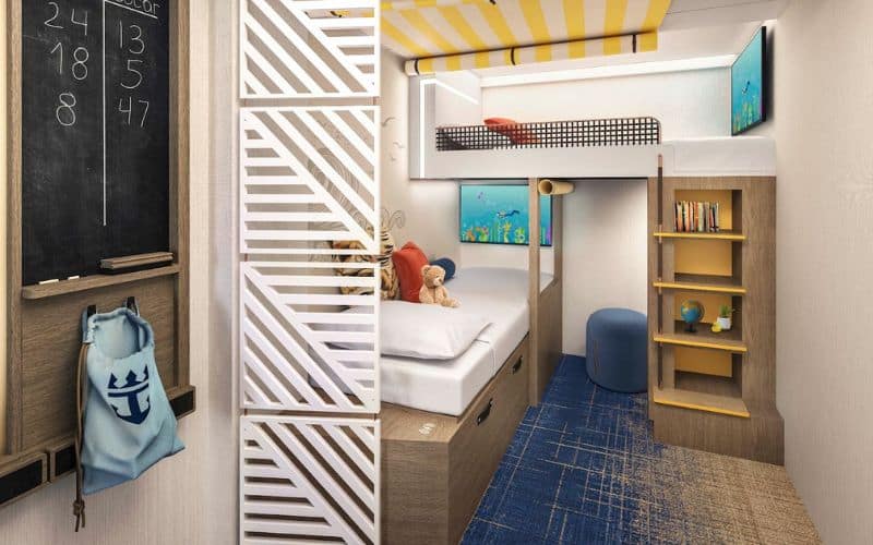 Family-friendly Infinite Ocean View Balcony stateroom on Royal Caribbean's 'Icon of the Seas.' The room features a cozy bunk bed setup with a bottom twin bed and a top loft-style bed, a playful yellow-striped ceiling, and nautical-themed décor. A small desk area with a chalkboard, books, and maritime-inspired accessories create a fun and inviting space for children.