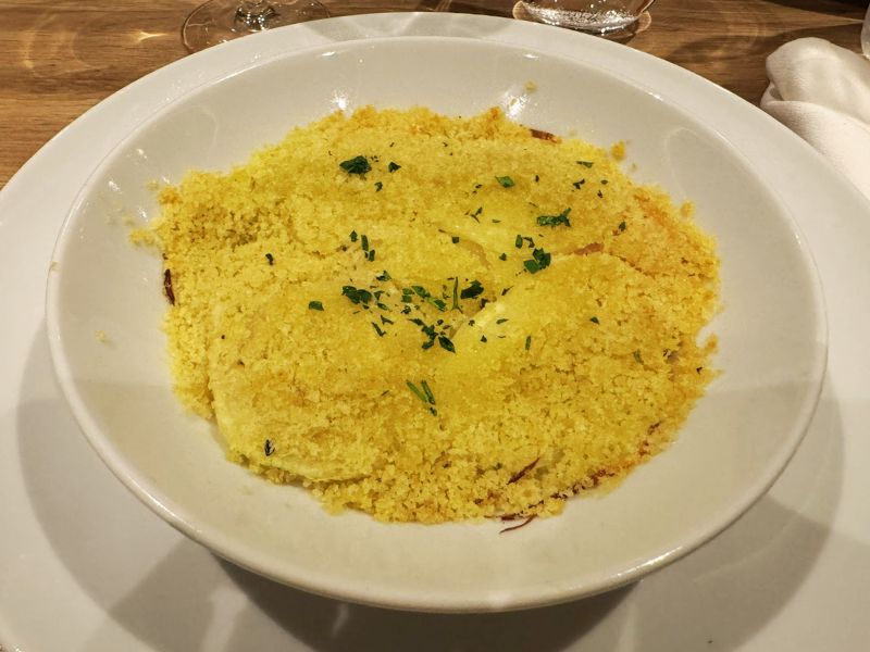 A plate of fluffy, golden couscous garnished with fresh herbs, presented on a white plate as part of a meal aboard the Costa Smeralda cruise ship.