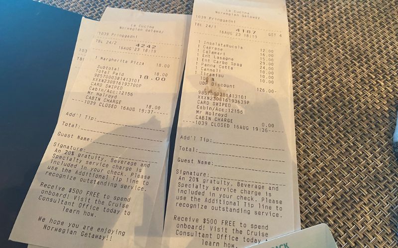 Two Norwegian Cruise Line receipts side by side, detailing the costs of various dishes and the 'Free at Sea' benefits, including a discount line item and a note about a $50 onboard credit, reflecting the perks of cruise dining packages.