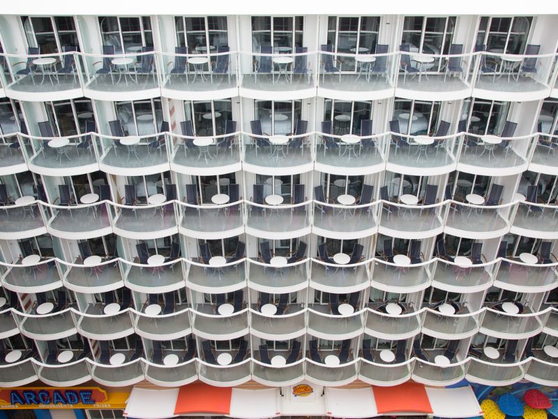 Symmetrical view of multiple tiers of balconies on Harmony of the Seas, with outdoor furniture visible, showcasing the ship's architectural design and passenger accommodation