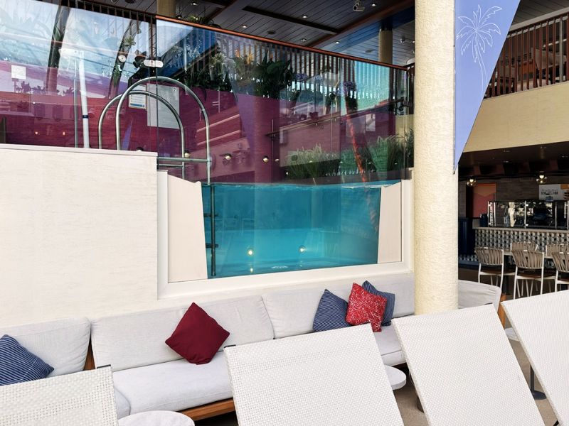 A comfortable lounge area on Costa Smeralda adjacent to an indoor jacuzzi with a transparent glass front, allowing for a unique view into the water, combining relaxation with modern design elements.