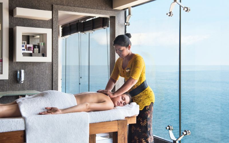 A tranquil spa experience onboard an MSC cruise ship, where a guest enjoys a relaxing massage from a professional therapist in a serene room with an ocean view, emphasizing wellness and relaxation at sea.