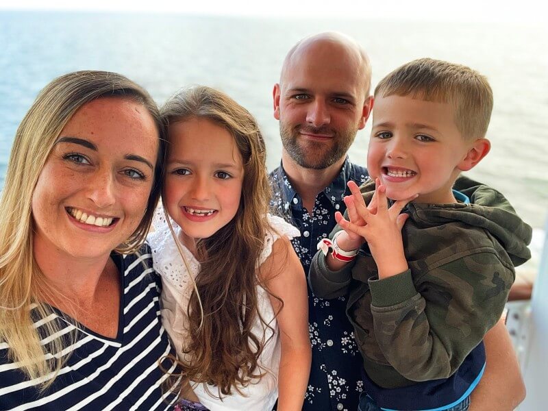 A family of four smiling for a photo on an MSC cruise ship, with the ocean visible in the background, capturing a happy moment during their vacation.