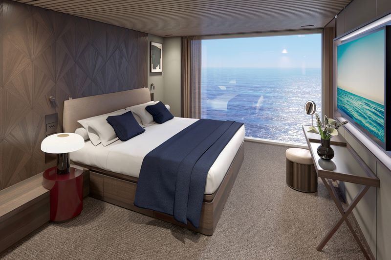 A sophisticated bedroom within The Haven on the Norwegian Cruise Line Aqua, featuring a king-sized bed with high-quality linens, a large window with ocean views, and a chic writing desk with a vase of fresh flowers.