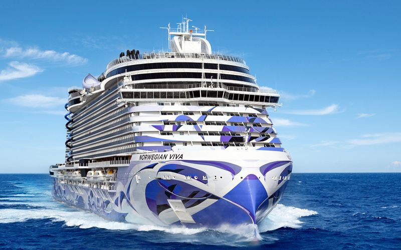 Norwegian Viva cruising the ocean with its blue and white majestic color matching the scene of the ocean and sky.