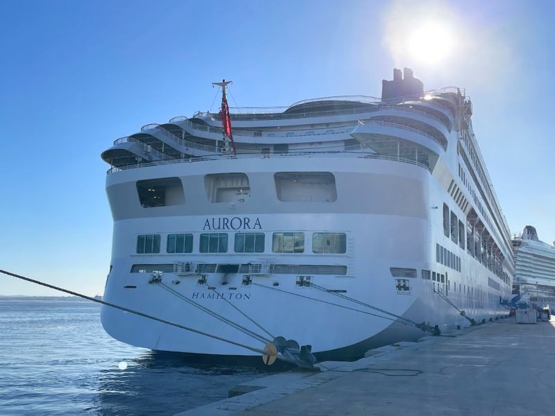 The P&O Aurora cruise ship docked, with the sun casting a glow over its aft cabins.