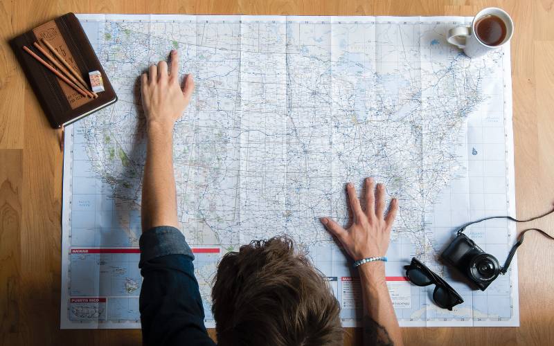 A man with a map laid out planning a trip.