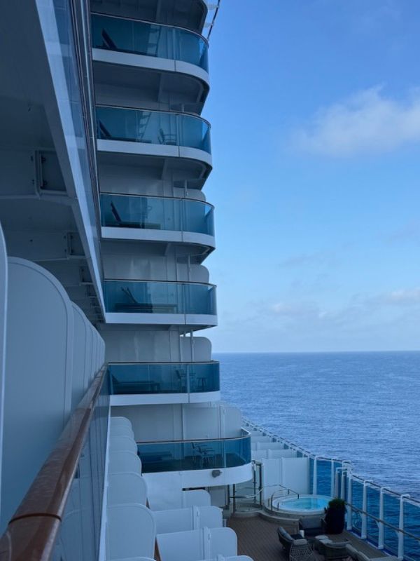 The image shows Firefly Park on Princess Cruises' Sun Princess, which appears to be a children's play area or activity center. The space is brightly lit and features a variety of activities, including long tables with red and blue chairs, an air hockey table, and a foosball table. There are also interactive screens on the walls, likely for gaming or educational activities. The floor is a mix of green carpet and wood-like vinyl, with playful, modern decor that creates a fun and engaging environment for kids. The area is spacious and well-organized, designed to keep young passengers entertained.