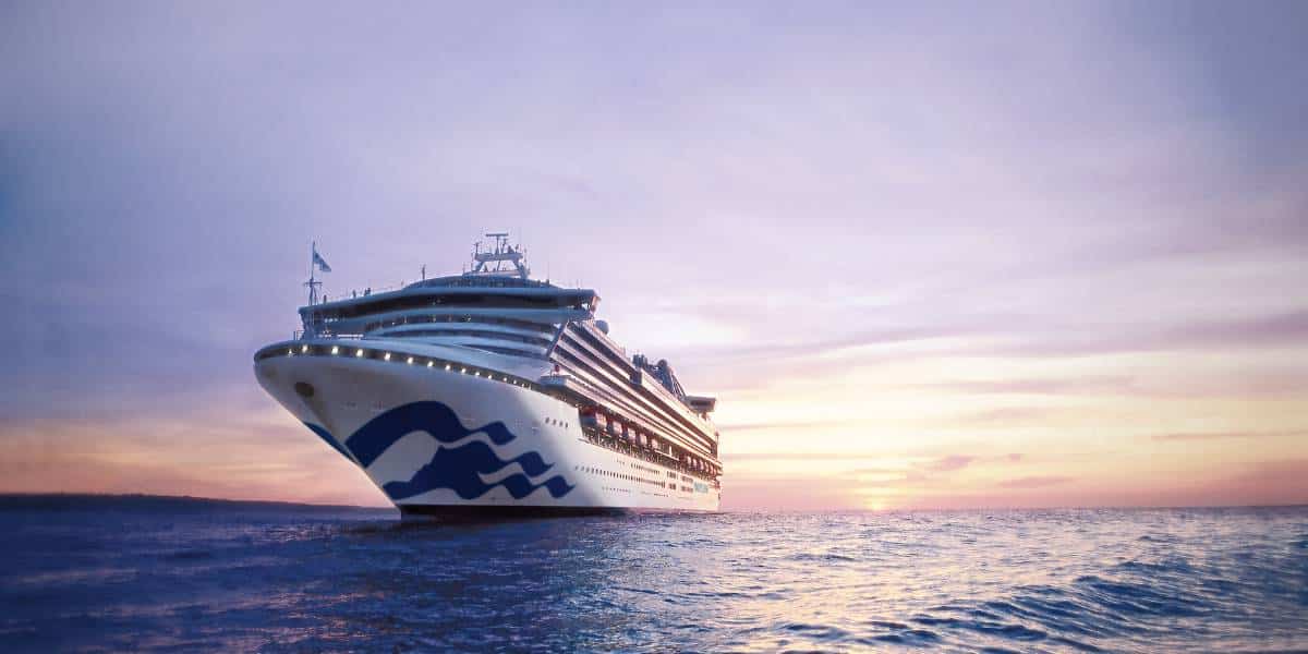 Sapphire Princess sailing on the water with a sunset behind the ship.