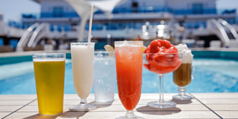 A variety of refreshing beverages arranged on a poolside table with a cruise ship in the background, capturing the essence of a luxurious vacation atmosphere.