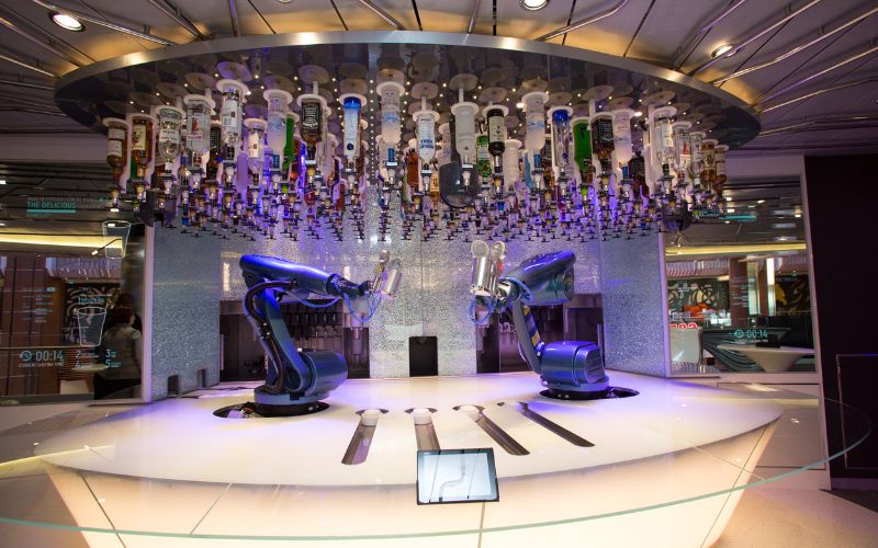 Futuristic Bionic Bar on Royal Caribbean's Quantum of the Seas, with robotic arms mixing drinks under an array of suspended liquor bottles, creating a cutting-edge entertainment and beverage experience at sea.