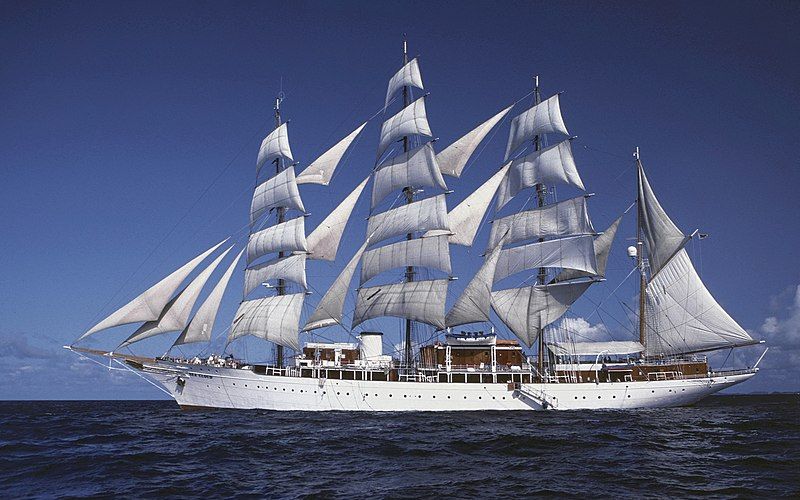 A majestic white sailing ship with billowing sails on the open sea.