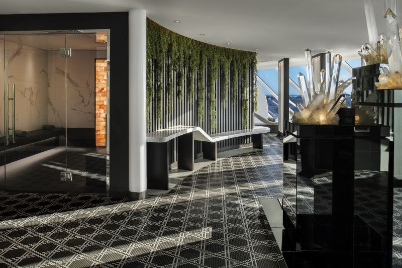 Interior of the SEA Thermal Suite on Celebrity Edge, featuring a sleek design with modern black and white decor, a wall of living plants, crystal sculptures, and reflective surfaces creating a tranquil and luxurious spa atmosphere.