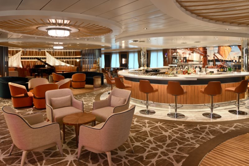 The elegant Schooner Bar on Icon of the Seas, with its stylish circular bar, comfortable seating areas, and a grand piano set in a warmly lit, inviting atmosphere for guests to relax and socialize.