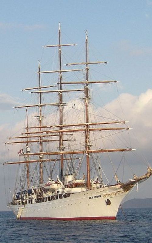A grand white sailboat with full sails cruising through the ocean.