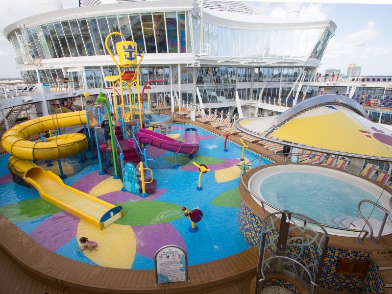 hildren's water park Splashaway Bay on Harmony of the Seas, with colorful water slides, splash pads, and a drench bucket, surrounded by sun loungers.