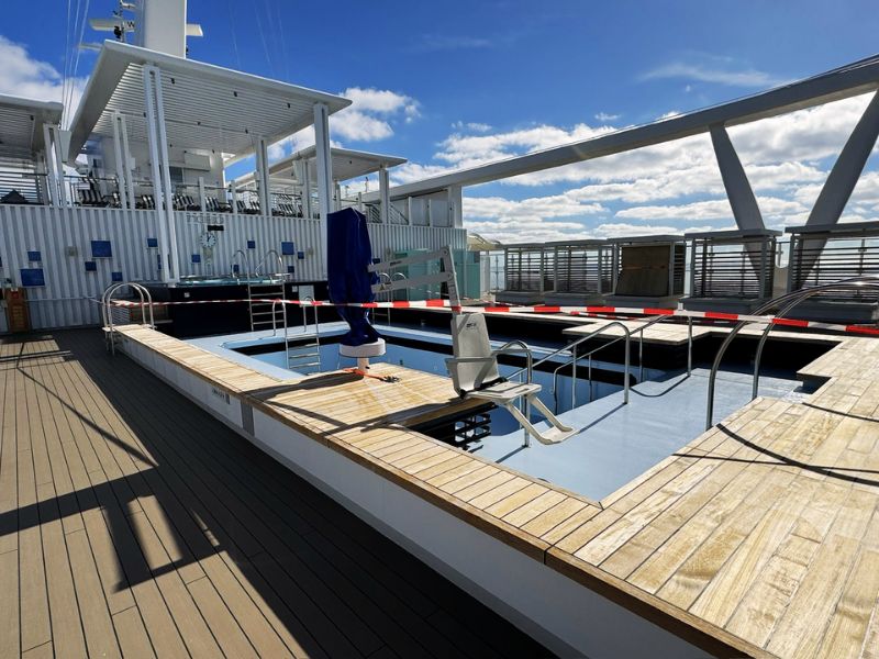 An outdoor pool roped off for maintenance on Costa Smeralda, featuring a calm water surface and a sunny deck area, indicating ongoing upkeep to ensure guest safety and amenities quality.