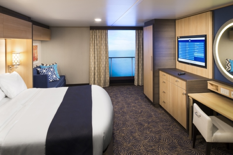 Interior of a Virtual Balcony room on Royal Caribbean's Anthem of the Seas, equipped with a large bed, contemporary furnishings, a work desk, and a floor-to-ceiling high-definition screen simulating a real-time ocean view.