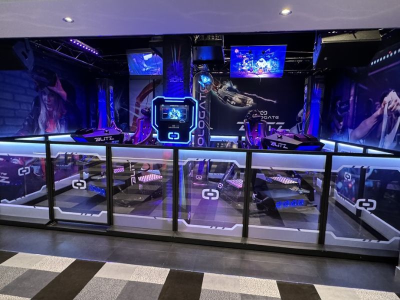 A high-tech virtual reality gaming area on MSC Euribia cruise ship, equipped with advanced VR gaming stations and illuminated with neon blue lights. The futuristic theme is enhanced by dynamic graphics and screens displaying immersive content.