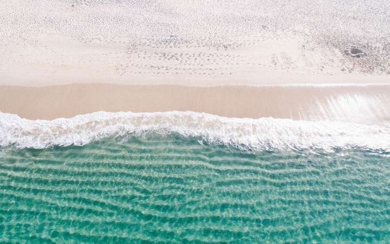 A birdseye view of about the beach with the gentle waves of the sea.