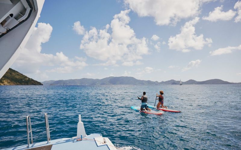 Two cruise guest paddle boarding