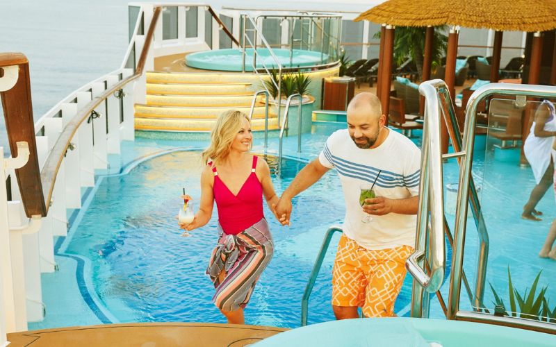 a couple holding a drink while having fun on honeymoon on a Carnival cruise