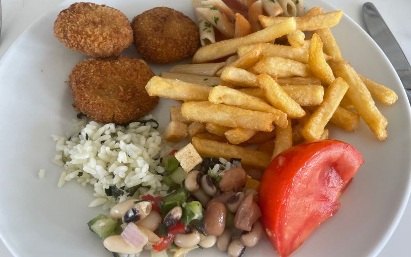 a plate with chips, pasta, rice, beans, and tomato