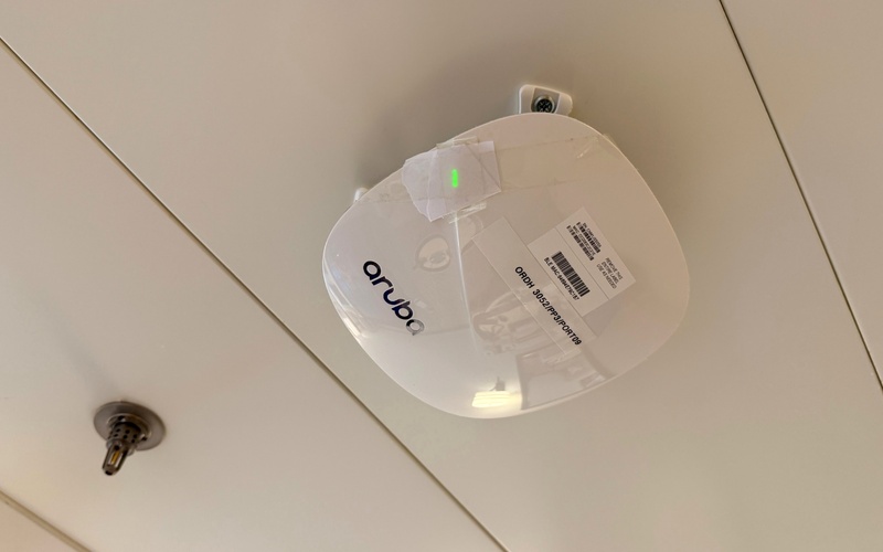 White circular cruise wifi device mounted on a cabin ceiling beside a sprinkler.