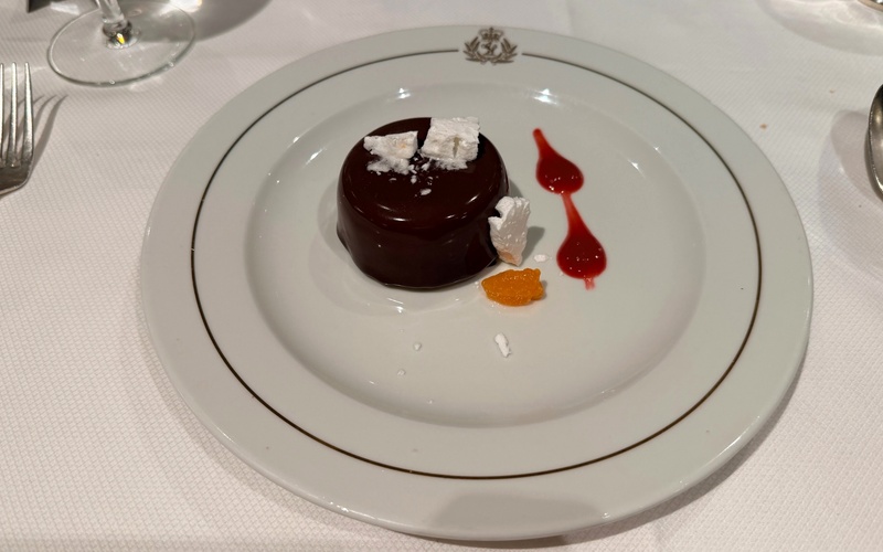 Small chocolate dessert decorated with merigue and colourful fruit sauces.