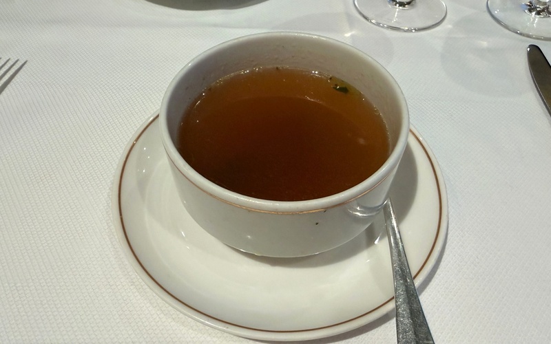 Onion soup served in a white cup and saucer.