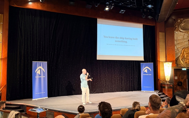 Speaker giving a presentation in a theatre, with the audience seated in front.