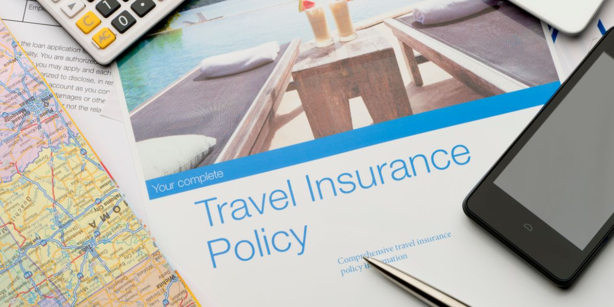 A brochure for 'Your complete Travel Insurance Policy' on a table with travel essentials, including a map, calculator, and smartphone, emphasizing the importance of comprehensive travel insurance for cruises.