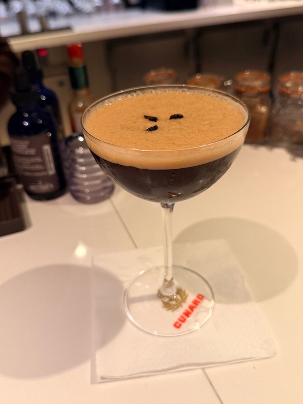 Espresso martini topped with coffee beans on a bar counter.