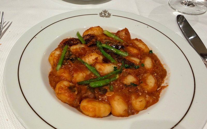 Gnocchi in tomato sauce topped with green vegetables.
