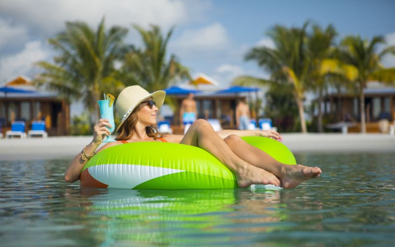 Woman enjoying her drink at Harvest Caye beach