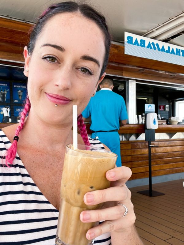 Woman on Celestyal Olympia's cruise holding a glass of iced coffee