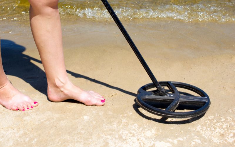 Woman using metal detector on the beach