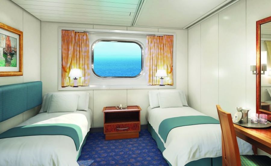 A bright and inviting Oceanview stateroom on the Norwegian Spirit, featuring two twin beds with white and teal bedding, a large picture window, and a cozy seating area, all decorated with warm lighting and nautical accents.