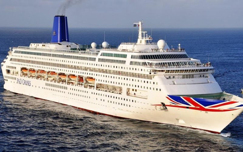 The P&O Oriana cruise ship, with its distinctive blue funnel and British flag design on the bow, cruising on the open sea under a clear blue sky.