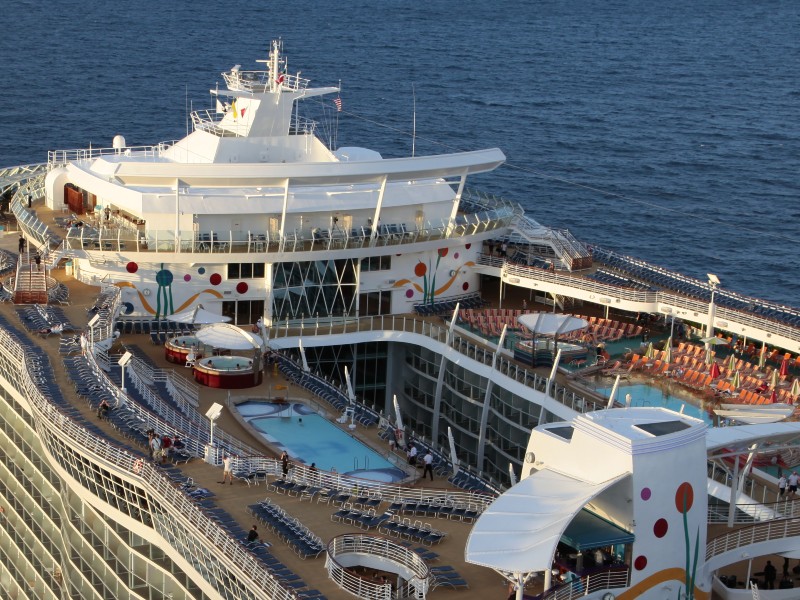 Close-up view of Allure of the Seas showing cabins located beneath the pool deck area, with sun loungers and a calm pool in the evening light, creating a vibrant atmosphere at sea.