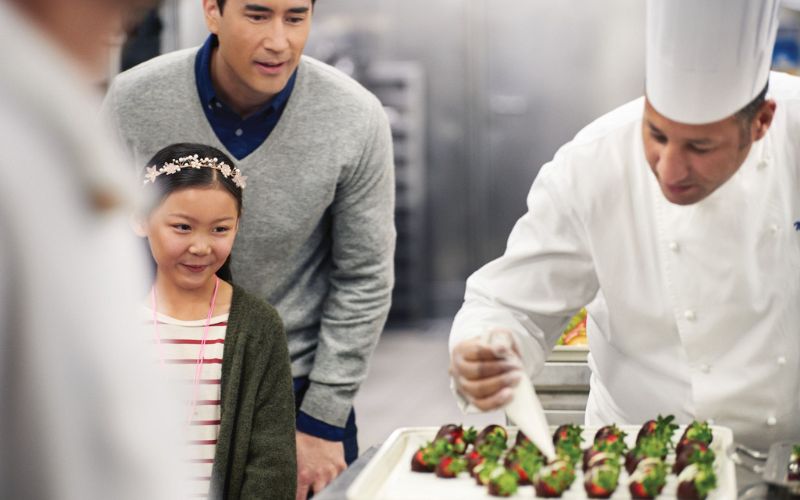 father and daughter watching the chef prepare food